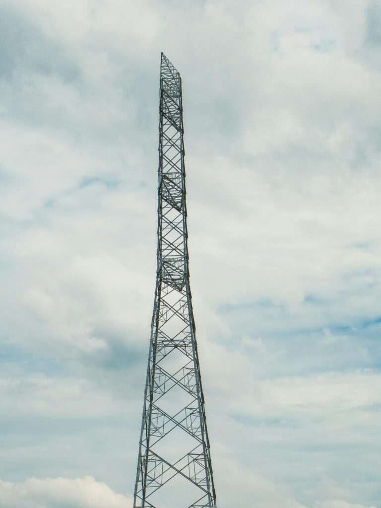 A towering communication tower set against a soft, cloudy sky in Dhaka Division, Bangladesh.